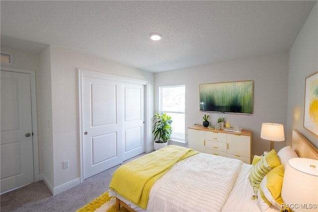 bedroom with light carpet and a closet