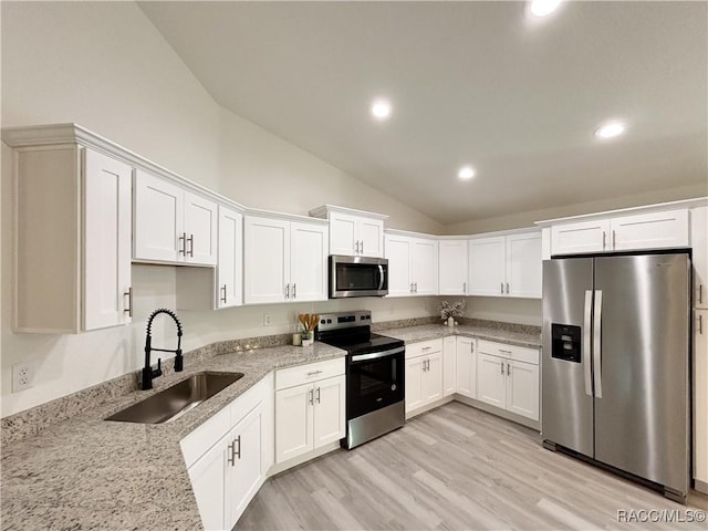 1370 SW Obee Ridge Rd, Dunnellon, FL 34430 - kitchen with stainless steel appliances, vaulted ceiling, white cabinets, light stone counters, and light wood-type flooring