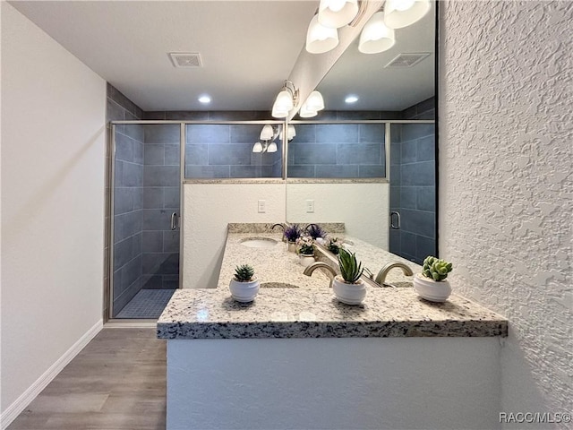 full bath featuring visible vents, a sink, a shower stall, and wood finished floors