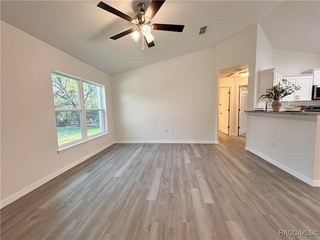 unfurnished living room featuring lofted ceiling, light wood-style flooring, visible vents, and baseboards