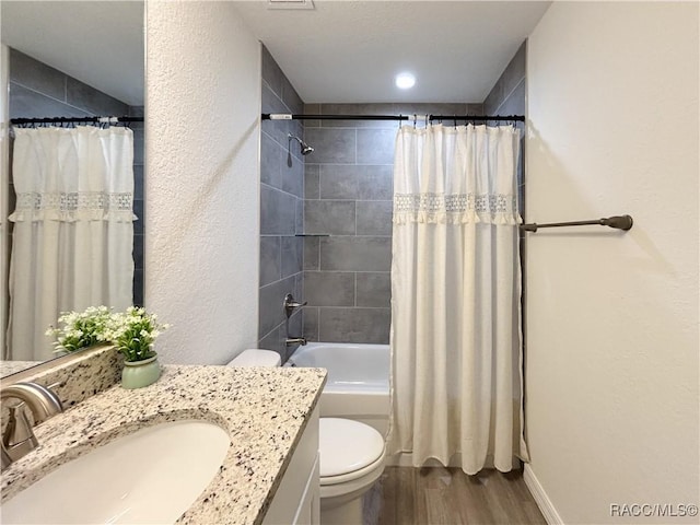 full bathroom with a textured wall, toilet, shower / tub combo, vanity, and wood finished floors