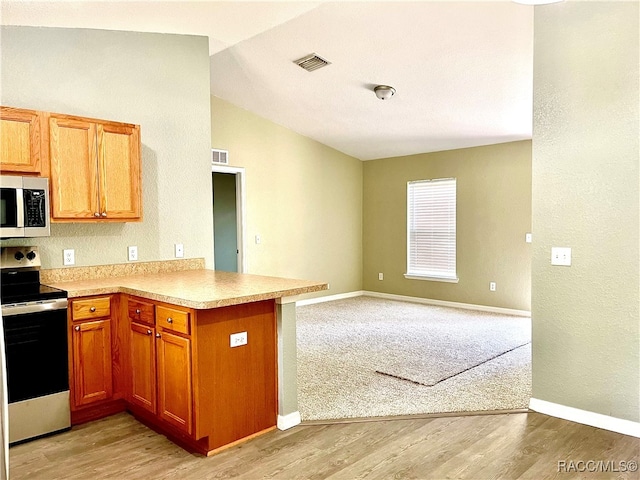 kitchen with kitchen peninsula, light wood-type flooring, lofted ceiling, and electric range oven