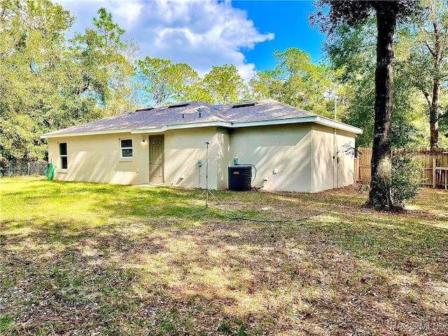 rear view of property featuring a yard and cooling unit