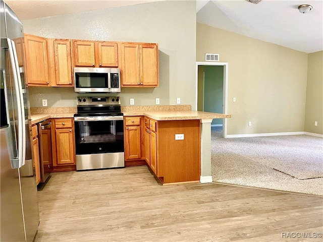 kitchen featuring kitchen peninsula, light hardwood / wood-style flooring, appliances with stainless steel finishes, and vaulted ceiling