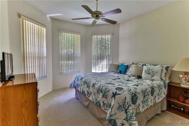 carpeted bedroom featuring ceiling fan and a textured ceiling