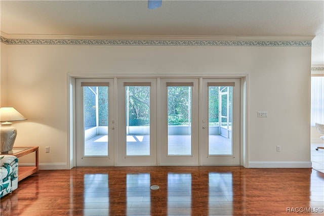 entryway with wood-type flooring, ornamental molding, and french doors