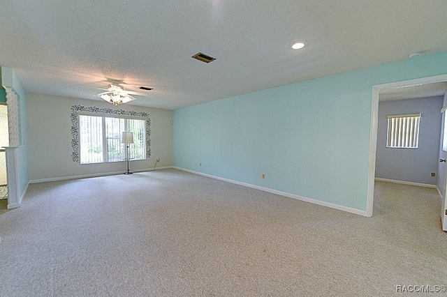 unfurnished room with a textured ceiling, ceiling fan, and light carpet