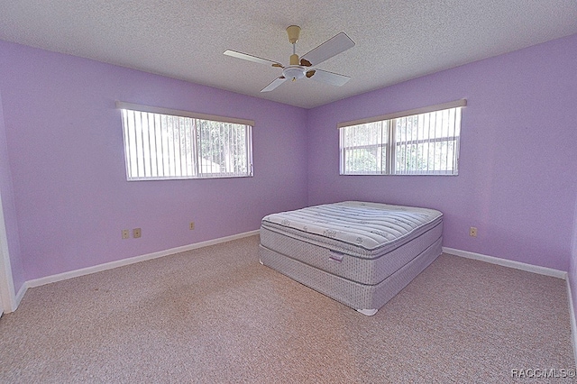 unfurnished bedroom with ceiling fan, a textured ceiling, and light carpet