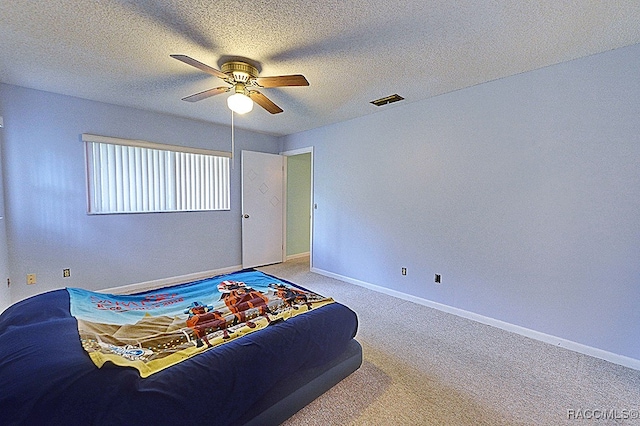 bedroom with ceiling fan, carpet floors, and a textured ceiling