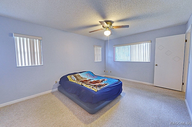 carpeted bedroom featuring ceiling fan and a textured ceiling