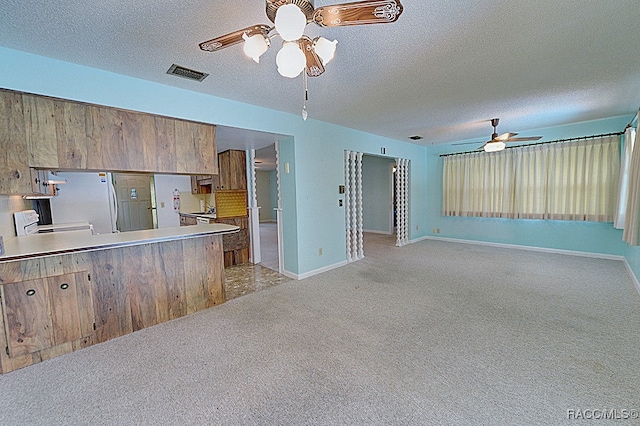 kitchen featuring kitchen peninsula, light colored carpet, and a textured ceiling