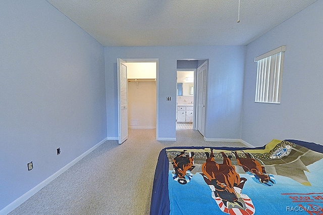 bedroom with a walk in closet, a textured ceiling, carpet floors, and a closet