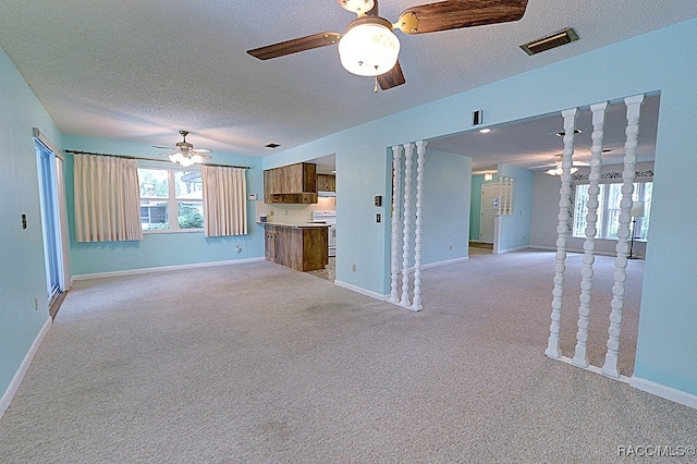 unfurnished living room featuring light carpet, ceiling fan, and a textured ceiling