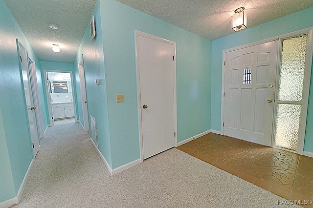 foyer featuring light carpet and a textured ceiling