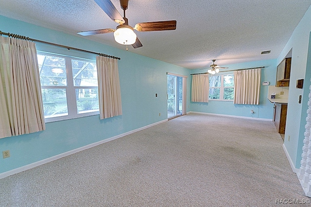 unfurnished living room with ceiling fan, light colored carpet, and a textured ceiling