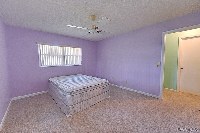 unfurnished bedroom with a textured ceiling, light colored carpet, and ceiling fan