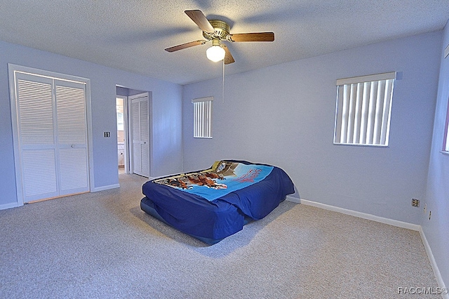 carpeted bedroom featuring multiple windows, a textured ceiling, and ceiling fan