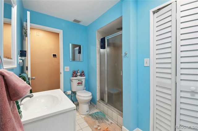 bathroom featuring toilet, vanity, tile patterned floors, and a shower with shower door