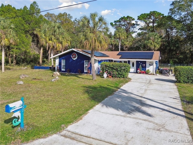 single story home featuring solar panels and a front lawn