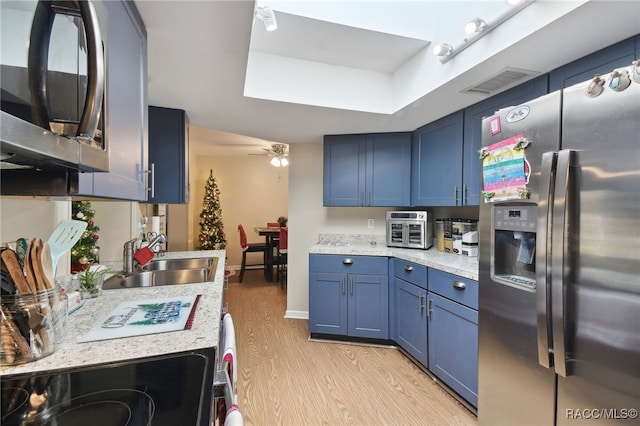 kitchen featuring blue cabinetry, stainless steel appliances, light hardwood / wood-style flooring, and sink