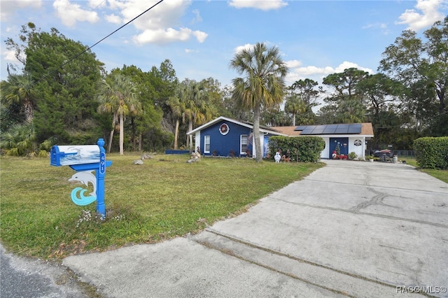 view of front of home with a front yard and solar panels