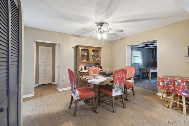 dining space with ceiling fan, a textured ceiling, and light hardwood / wood-style flooring