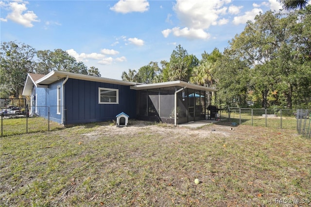 back of property with a sunroom and a lawn