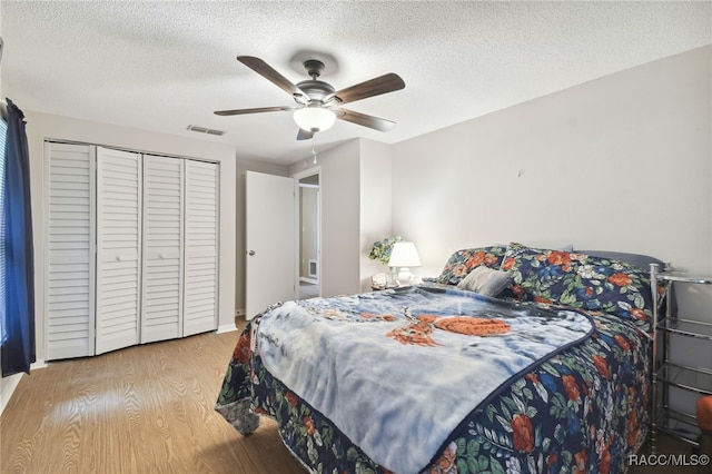 bedroom with a textured ceiling, a closet, light hardwood / wood-style flooring, and ceiling fan