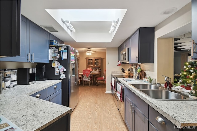 kitchen featuring a raised ceiling, sink, ceiling fan, appliances with stainless steel finishes, and light hardwood / wood-style floors