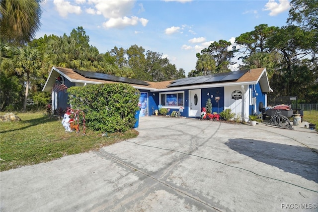 ranch-style home with solar panels and a front lawn