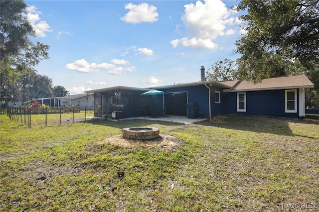 back of property featuring a fire pit and a lawn