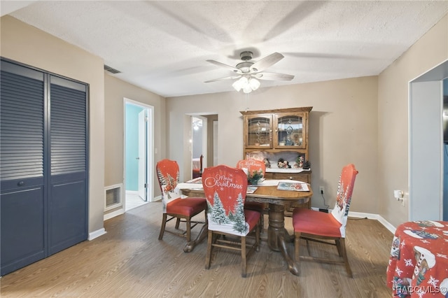 dining space featuring hardwood / wood-style flooring, ceiling fan, and a textured ceiling