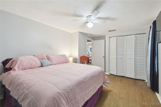 bedroom with ceiling fan, a closet, light hardwood / wood-style floors, and a textured ceiling