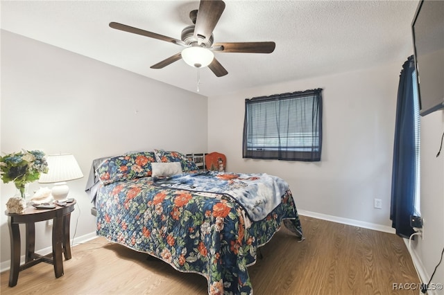 bedroom featuring ceiling fan, wood-type flooring, and a textured ceiling