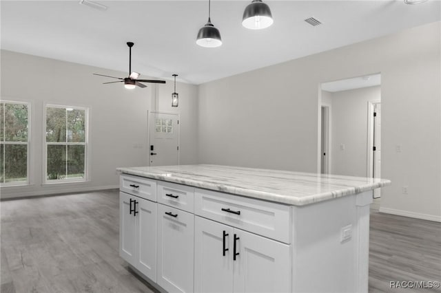 4911 S Skyblue Dr, Inverness, FL 34452 - kitchen with white cabinets, light wood-style flooring, a kitchen island, light stone counters, and pendant lighting