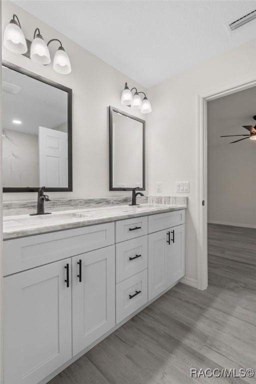 4911 S Skyblue Dr, Inverness, FL 34452 - bathroom with double vanity, visible vents, a ceiling fan, a sink, and wood finished floors