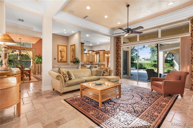 living room with a towering ceiling, ceiling fan with notable chandelier, and ornamental molding