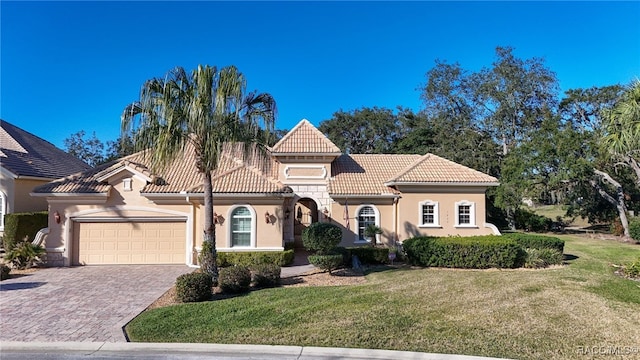 mediterranean / spanish house featuring a garage and a front lawn