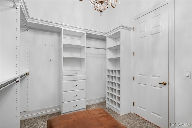 walk in closet featuring light colored carpet and a chandelier