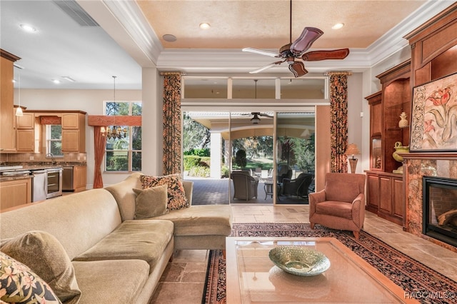 living room with sink, ceiling fan, crown molding, and a premium fireplace