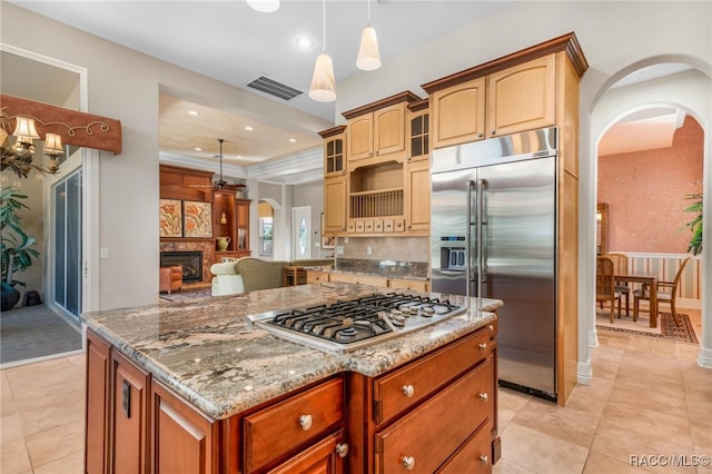 kitchen with light stone countertops, light tile patterned flooring, decorative light fixtures, a kitchen island, and appliances with stainless steel finishes