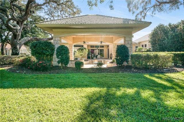 rear view of property with a lawn and ceiling fan