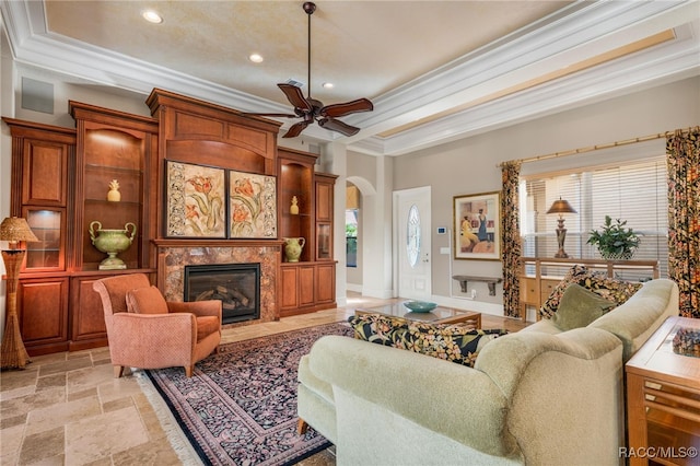 living room featuring a high end fireplace, ceiling fan, and crown molding