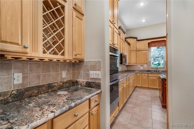 kitchen with light tile patterned flooring, sink, appliances with stainless steel finishes, and dark stone counters