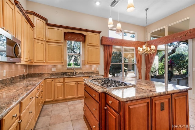 kitchen featuring pendant lighting, a center island, sink, light tile patterned floors, and stainless steel appliances