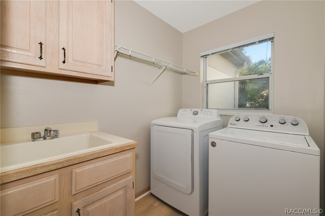 laundry room featuring washer and dryer, light wood-type flooring, cabinets, and sink