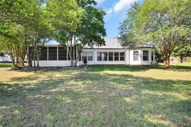 rear view of property with a yard and a sunroom