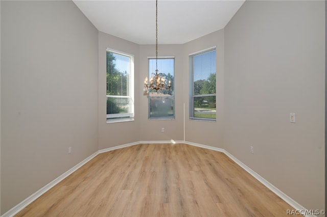 empty room with a chandelier and light wood-type flooring