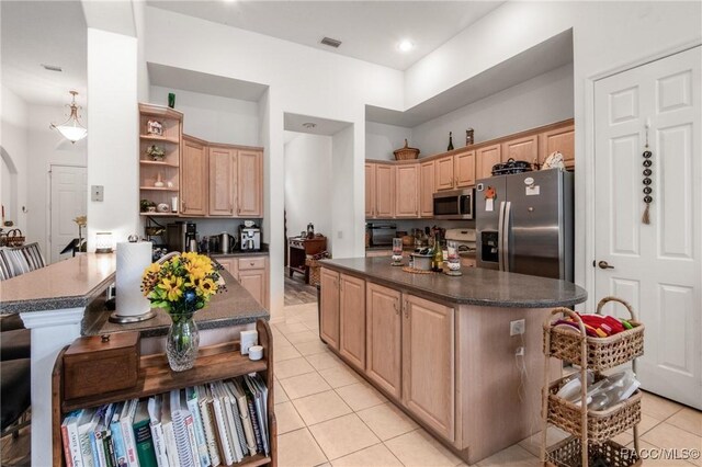 kitchen with light brown cabinetry, a center island, stainless steel appliances, and light tile patterned flooring