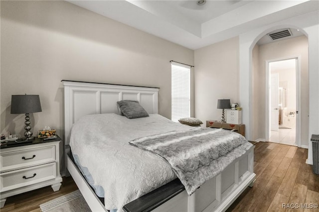 bedroom featuring ensuite bathroom and dark hardwood / wood-style flooring